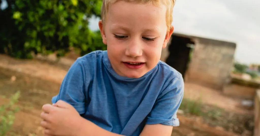 A boy scratches his arm.