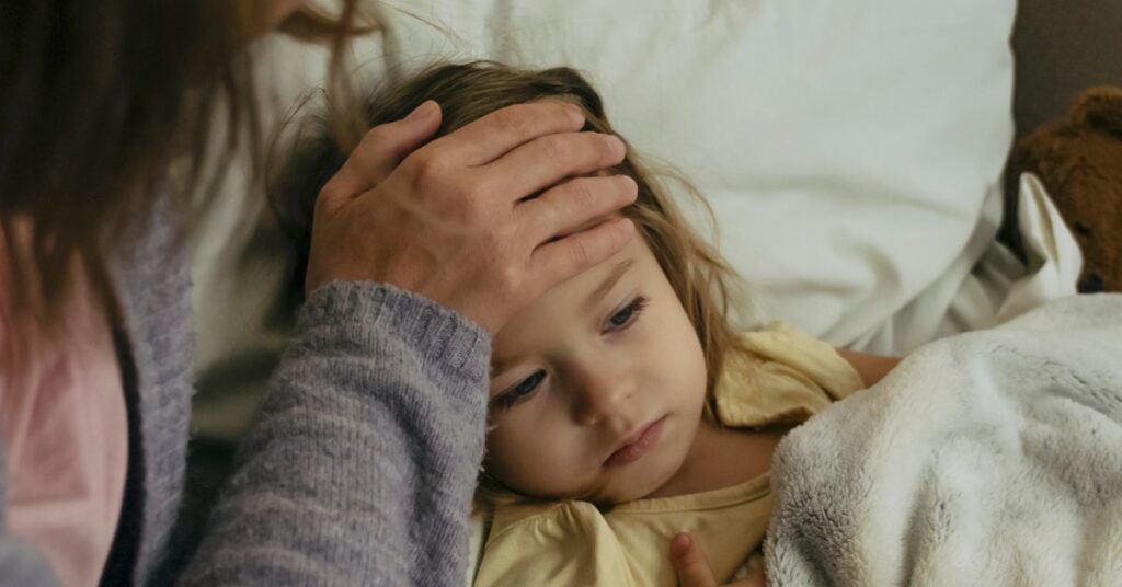 A mother feels the forehead of her feverish child.