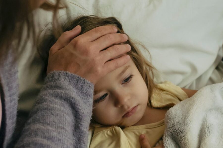 A mother feels the forehead of her feverish child.