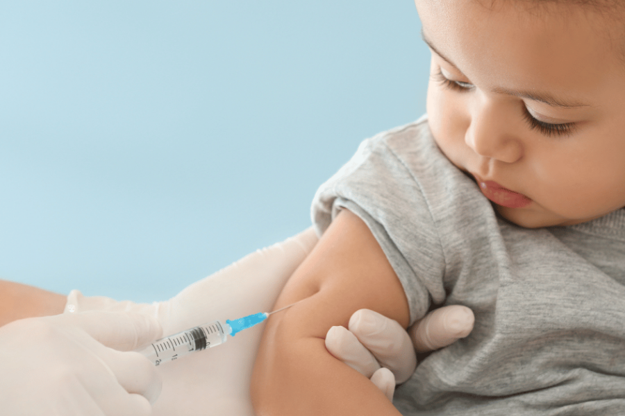A baby receives a vaccine shot in the arm.