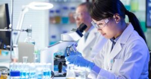 A scientist examines a vaccine sample through a high-powered microscope.