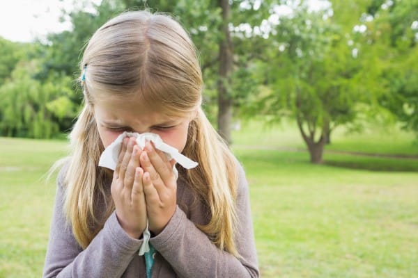 A young girl blows her nose.