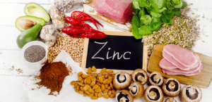 Several zinc-rich foods, including mushrooms, meats, nuts, and vegetables, lay on a table.