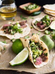 Three beef tacos served with lime and cilantro. 