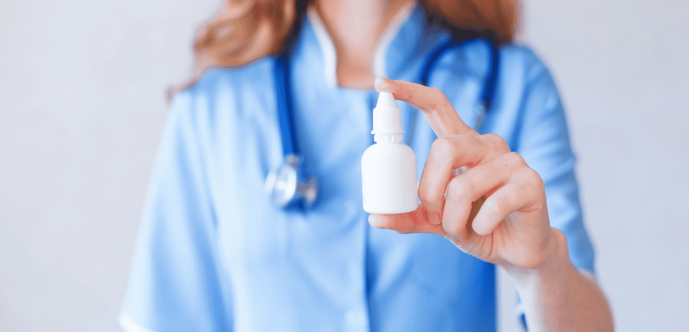 A doctor holds a bottle of antiseptic nasal spray.