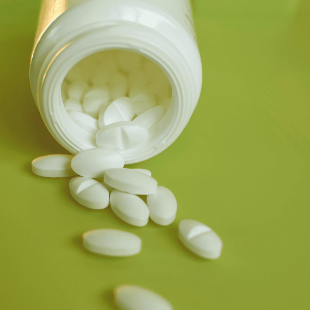 An open bottle of painkillers lies tipped on its side. A few pills have spilled out onto the counter.