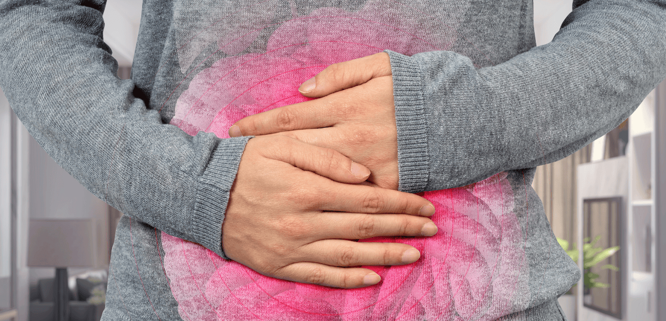A young woman holds two hands over her ailing stomach.