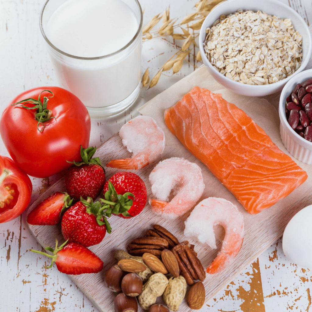 Salmon, shrimp, strawberries, nuts, oatmeal, beans, tomatoes, and milk neatly displayed on a table. 