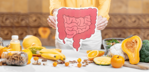 A woman standing in a kitchen holds a picture of the digestive tract over a counter laden with healthy foods.