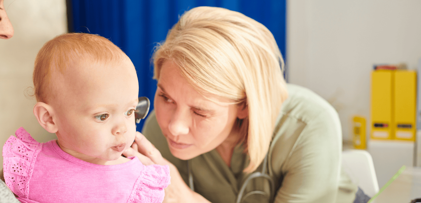 A pediatrician looks into a baby's ear with an otoscope.