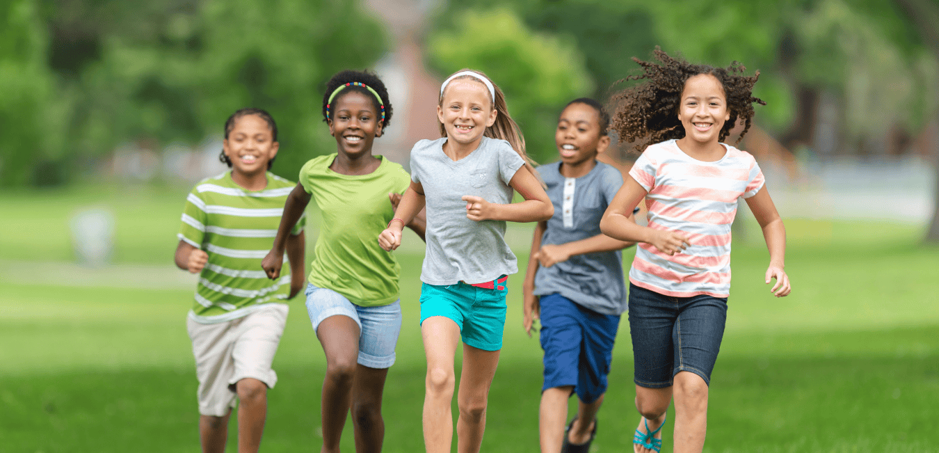 Five children running outdoors in a green field.