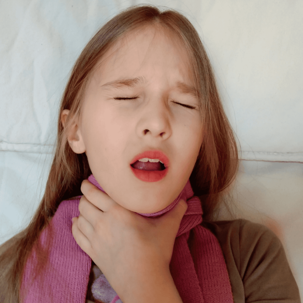 A young girl grasps her throat as she coughs. 