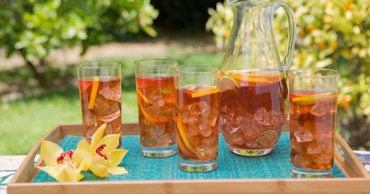 A pitcher of herbal iced tea and four glasses neatly arranged on a serving tray.