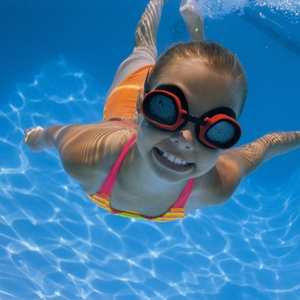 child swimming in pool with goggles