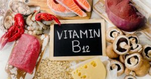 A sign that says "vitamin B12" lies centered on a table surrounded by raw fish, organ meats, beef, and cheese.