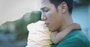 A distressed father holding a young child.