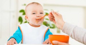 A baby eats a beef liver supplement that is mixed into his pureed food.