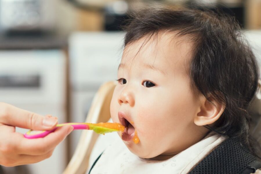 A baby eats a bite of baby food.