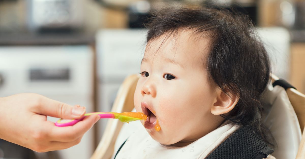 A baby eats a bite of baby food.