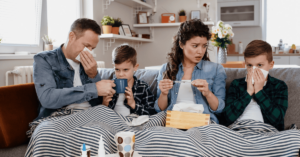A sick family sips immune-boosting tea while sitting together on a couch.