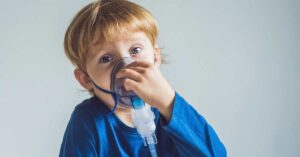 Boy holding respirator to face