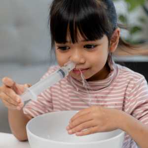 A girl uses warm saline water to rinse her sinuses.