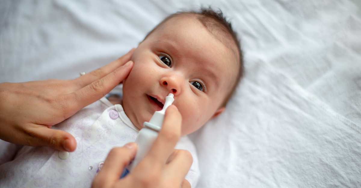 A baby receives a saline sinus rinse to relieve nasal congestion.