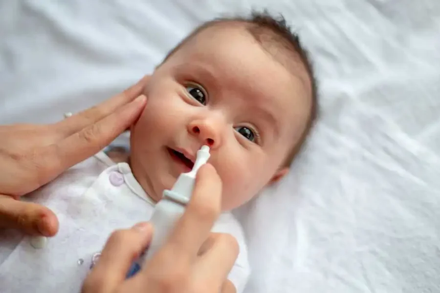 A baby receives a saline sinus rinse to relieve nasal congestion.