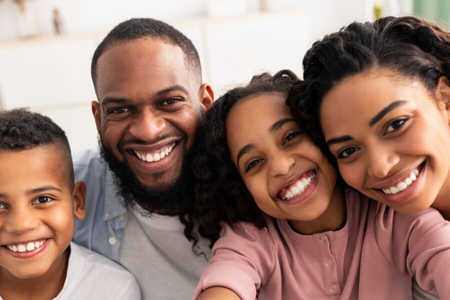 A happy family smiles while taking a selfie.