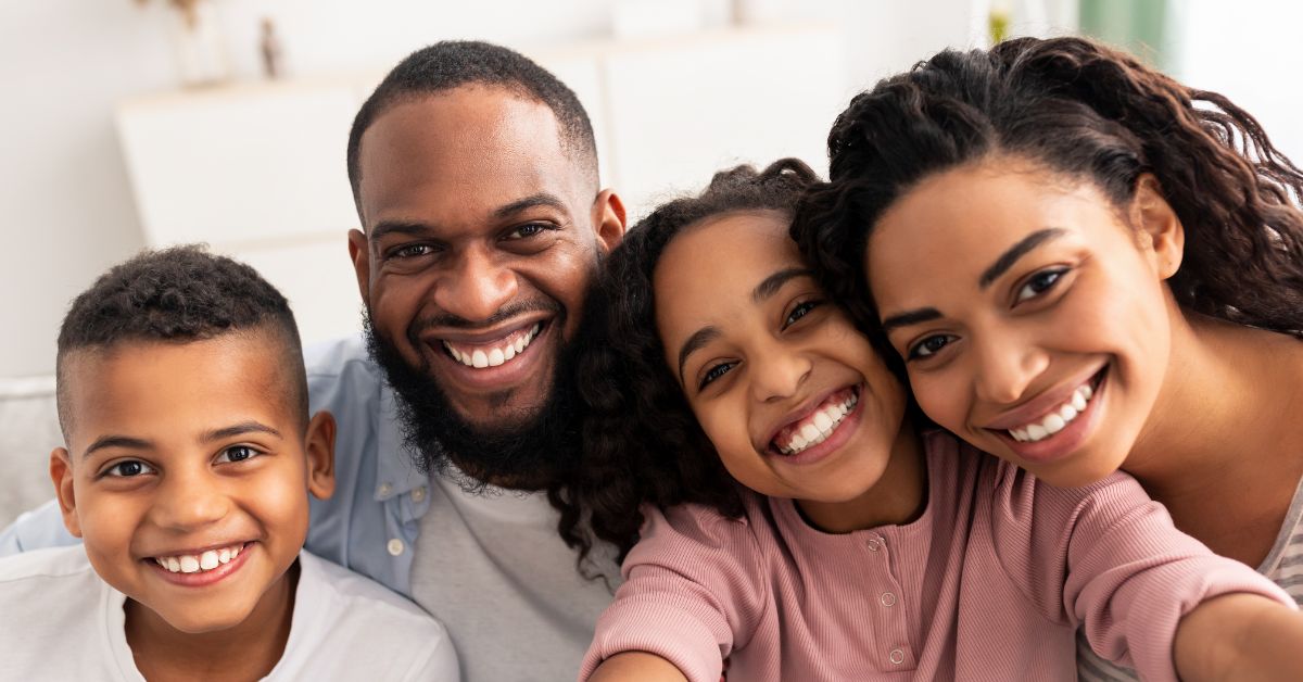 A happy family smiles while taking a selfie.