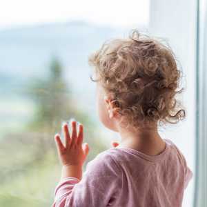 A young child gazes out the window.
