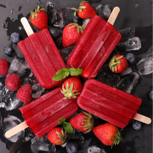 Bright red hibiscus popsicles surrounded by berries.