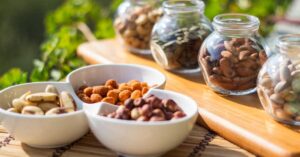 Bowls and jars full of melatonin rich nuts rest on a wooden table.