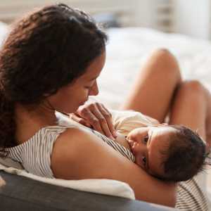 A woman breastfeeds a young infant.