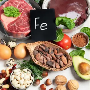 Several dietary sources of iron on a white surface, such as beef, beef liver, and spinach.