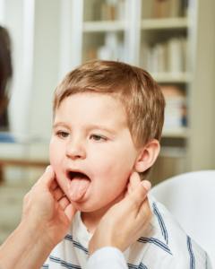 A doctor checks the mouth and neck of an ill child.