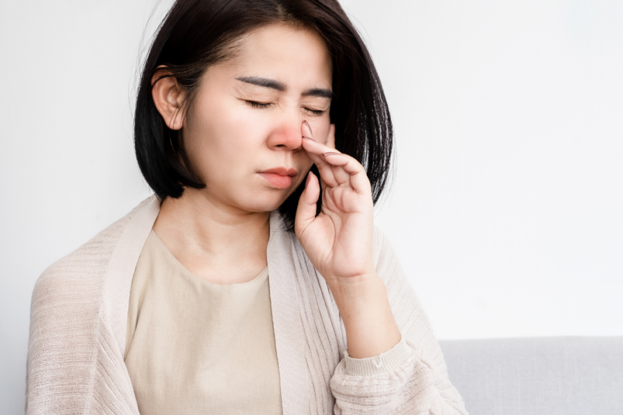 A woman with sinus pressure rubs her nose.