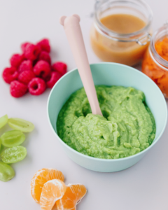 Healthy food options for babies: avocado, raspberries, sweet potato, and sliced fruits.