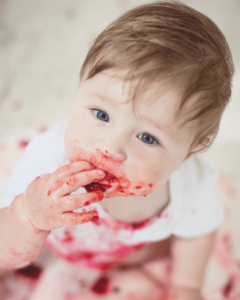 A baby eats raspberries.