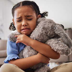 An anxious young girl squeezes her stuffed animal.