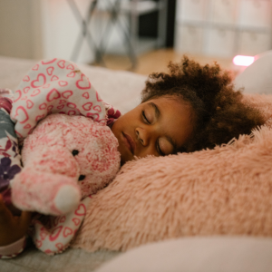 A young girl holds her stuffed animal while sleeping.