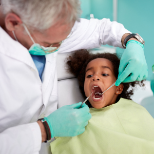 A dentist checks a young girl's teeth. 