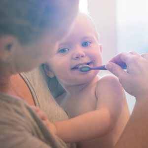 A mother gently brushes her toddler's teeth.