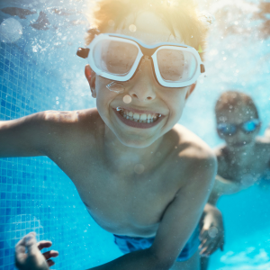 Two boys wearing goggles swim underwater.