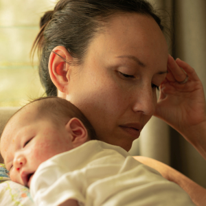An anxious mother holds her sleeping infant.