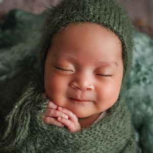 A young infant bundled in a green blanket sleeps peacefully.