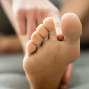 A finger itches between toes on a foot.