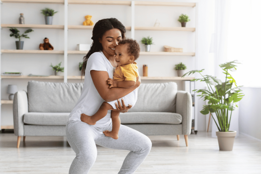 A mom squats while holding her baby.