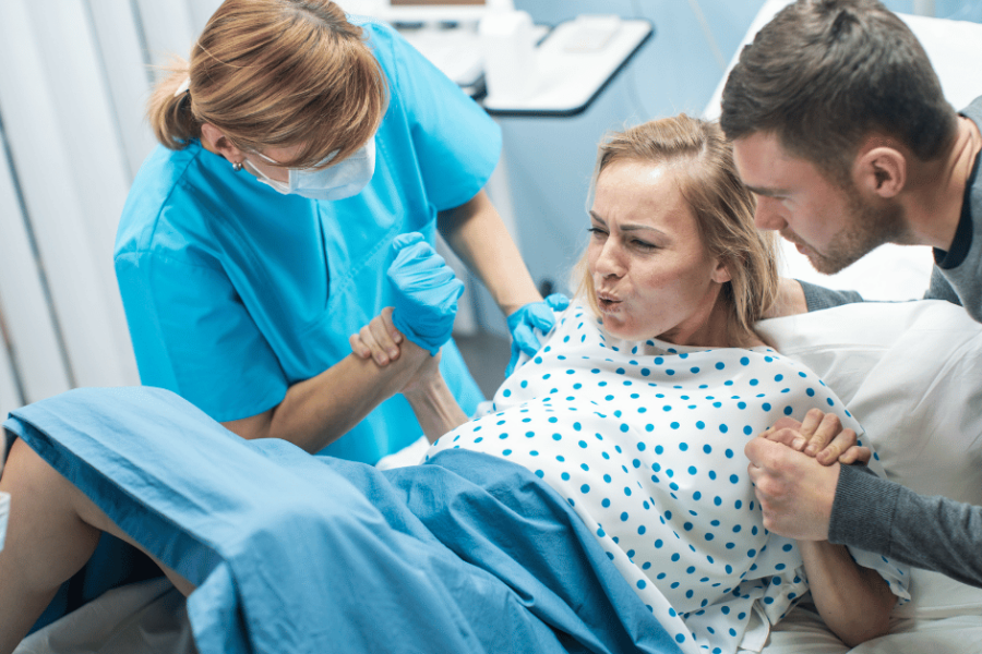 A woman giving birth is surrounded by doctors and nurses.