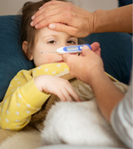 A parents feels their child's forehead while taking their temperature.